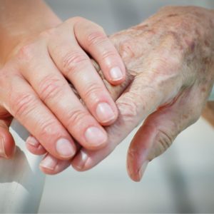 Nurse Holds The Hand Of Elderly Assisted Living Resident.