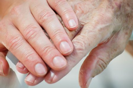 Nurse holds the hand of elderly assisted living resident.