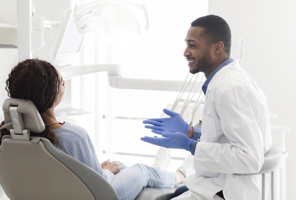 Friendly Black Dentist Explaining Patient Treatment Plan