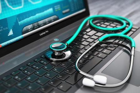 A doctor's stethoscope sits on a computer keyboard.