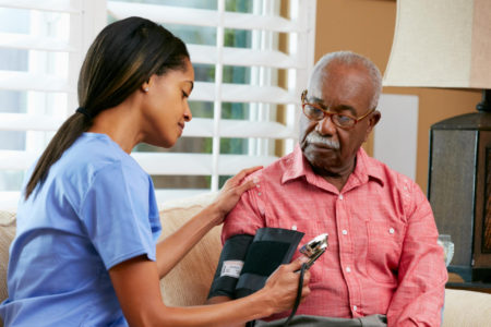 A nurse tests the blood pressure of a senior in his home.