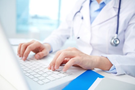 A Doctor Looks At Patient Data On A Computer.