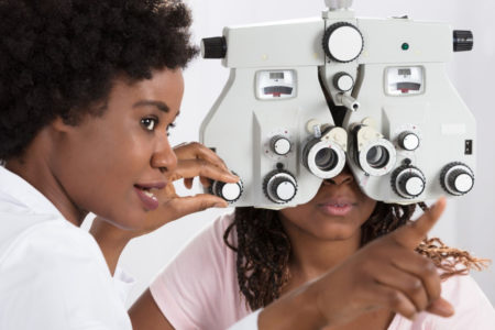 female optometrist performs eye exam on patient